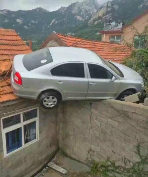 青岛崂山区雕龙嘴村。一司机倒车倒大了，冲上了村民的屋顶。